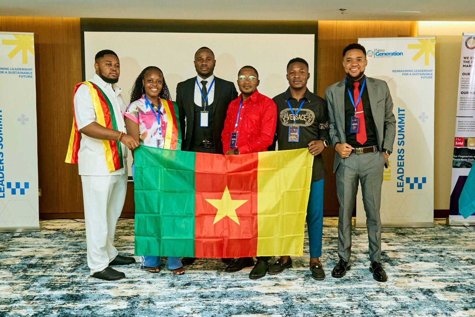 Six delegates holding the flag of Cameroon in front of the summit banner