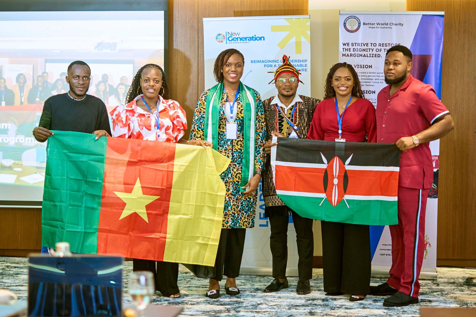 Delegates holding the flags of Cameroon and Kenya in front of the summit banners