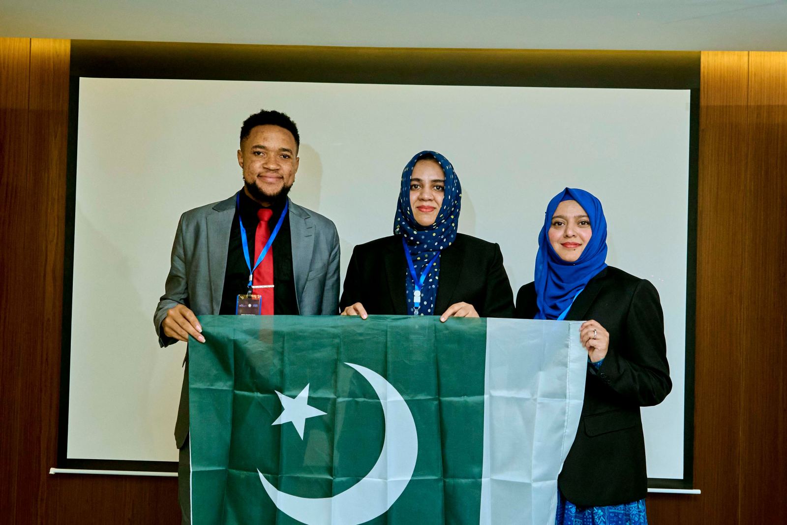 Three delegates holding the flag of Pakistan